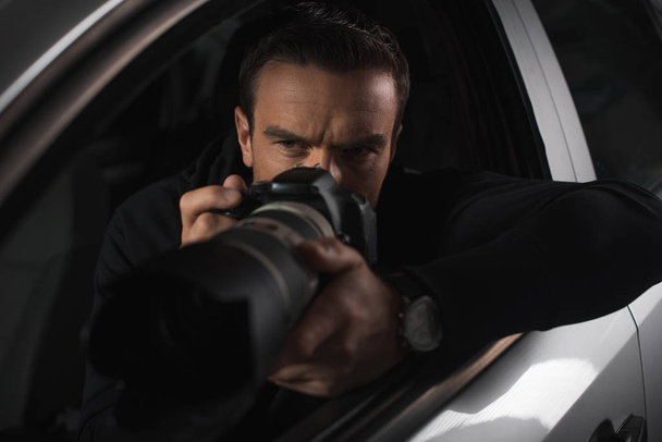 concentrated paparazzi spying by camera with object glass from his car  - Foto, Imagen