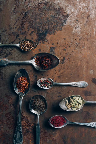 top view of spices in spoons on grungy tabletop - Fotó, kép