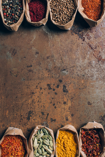підвищений вид на індійські спеції в паперових мішках на коричневому гранжевому столі
 - Фото, зображення