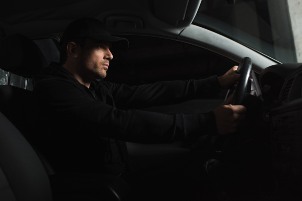 vista lateral de paparazzi masculino concentrado haciendo vigilancia y coche de conducción
  - Foto, Imagen