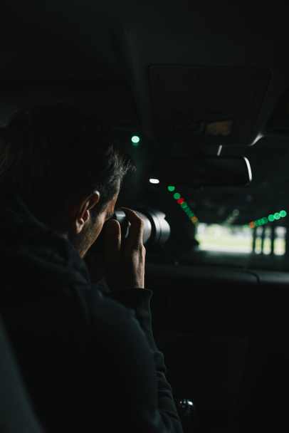 vista posteriore dell'uomo che fa sorveglianza con telecamera con oggetto di vetro dalla sua auto
 - Foto, immagini
