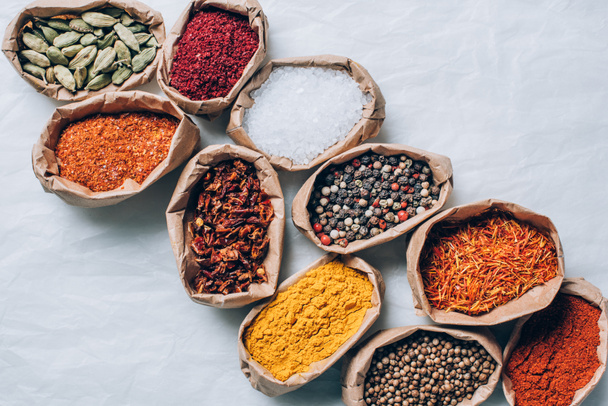 top view of colorful spices in paper bags on white table - Photo, Image