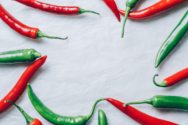 top view of red and green chili peppers on white tabletop - Фото, изображение