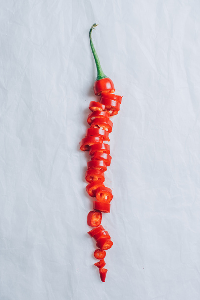 top view of cut red chili pepper on white table - Foto, Imagen