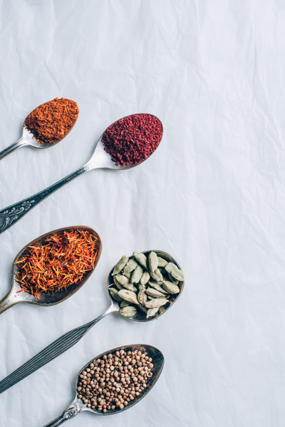 top view of dry spices in spoons on white table - Foto, afbeelding