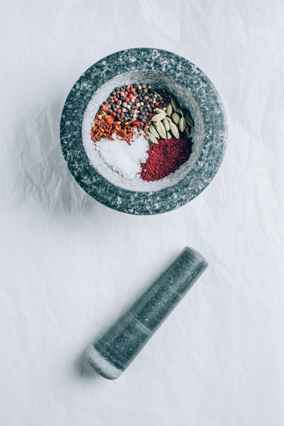 elevated view of mortar with spices and pestle on white table - Photo, Image