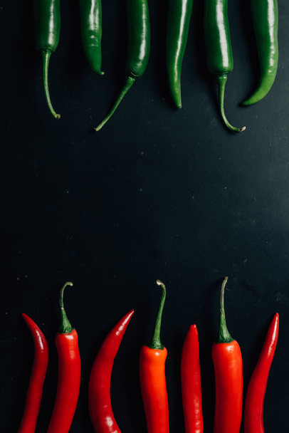 top view of red and green chili peppers on dark table - Foto, Bild