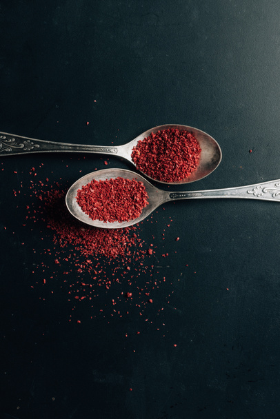 Top view of chili pepper in spoons on dark table - 写真・画像