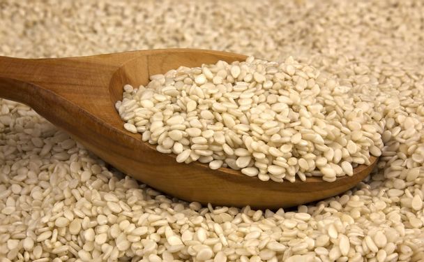 Heap of white sesame seeds with wooden spoon  - Photo, Image