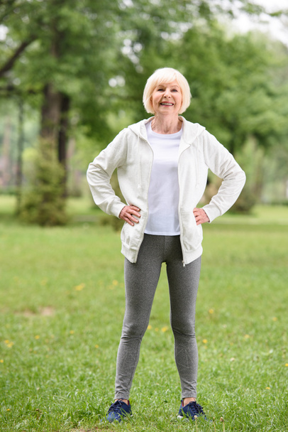 elderly sportswoman standing on green lawn in park - Fotoğraf, Görsel
