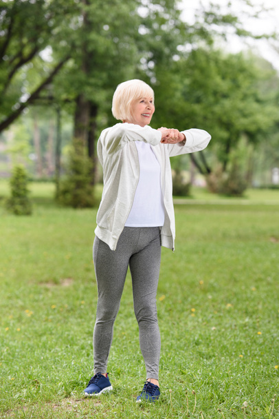 senior caucasian sportswoman exercising on green lawn in park - Foto, Imagem