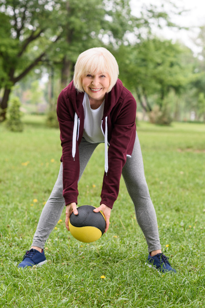 старша жінка тренується з медичним м'ячем у парку
 - Фото, зображення