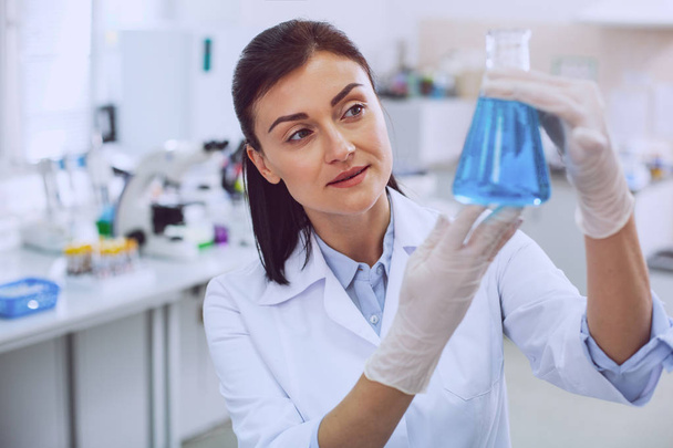 Delighted female researcher holding a tube - Foto, Imagen
