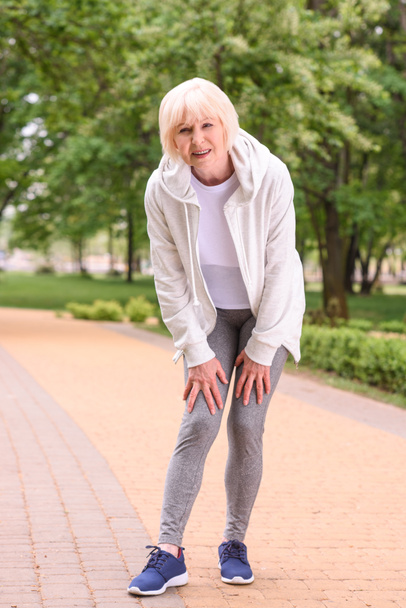elderly sportswoman with knee pain standing in park - Photo, Image