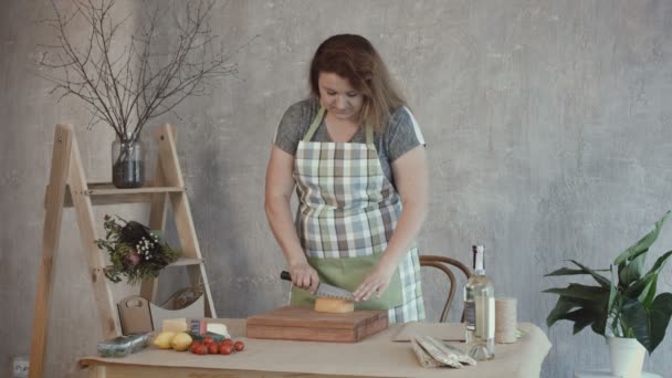 Lovely woman cutting delicious cheese on board - Imágenes, Vídeo