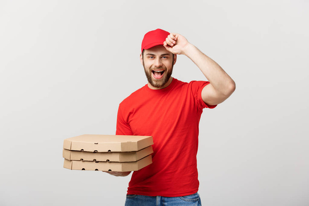 Concetto di consegna: corriere uomo consegna pizza bello in uniforme rossa con tappo contenente scatole di pizza. Isolato su bianco
. - Foto, immagini