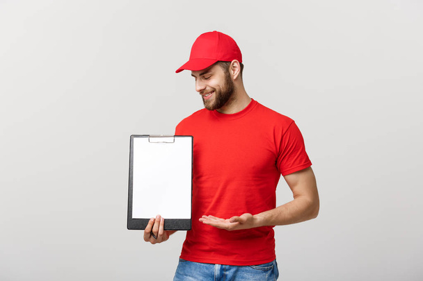 Delivery man in red uniform holding white empty blank paper isolated on white background. Copy space advertisement. Place for text or image - Fotó, kép
