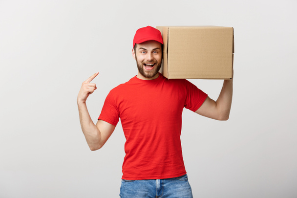 Delivery Concept - Portrait of Happy Caucasian delivery man pointing hand to present a box package. Isolated on Grey studio Background. Copy Space. - Фото, зображення