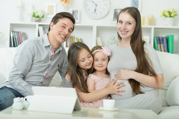 happy pregnant woman with husband and children sitting on sofa at home - Φωτογραφία, εικόνα