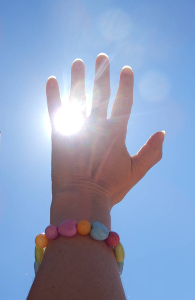 女の子の手を太陽の光と青空をキャッチのカラー詳細写真。救いの手の詳細. - 写真・画像