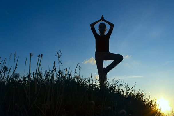 Adolescente em uma posição de equilíbrio Yoga. Rapariga em posição de dose de árvore, ao ar livre
. - Foto, Imagem