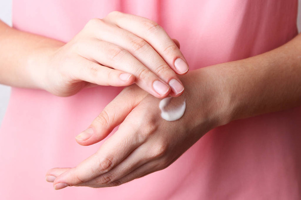A menina mancha mãos com uma nata cosmética de partida de um jovem e elasticidade de uma pele. cuidados pessoais. minimalismo, o topo
 - Foto, Imagem