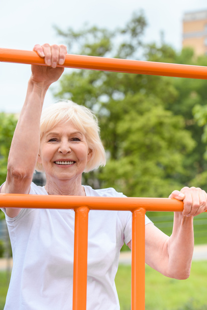sorridente sportiva anziana che si esercita sul terreno sportivo
 - Foto, immagini