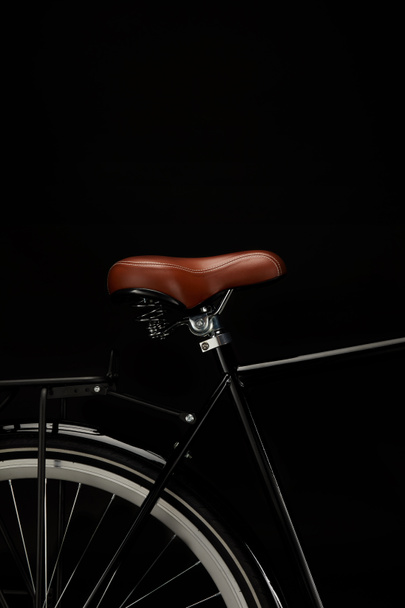 close-up view of saddle and wheel of vintage bicycle isolated on black - Фото, зображення