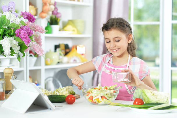 Cute girl preparing delicious fresh salad in kitchen - 写真・画像