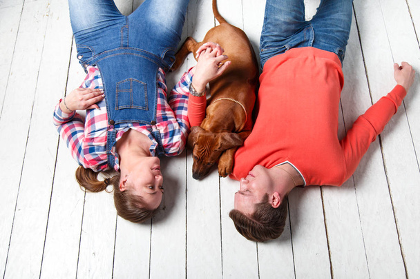 Young couple playing with their puppy. The concept of a happy family life. - Foto, Bild