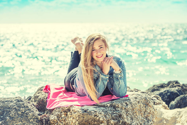 portrait of young beautiful woman lying down on the stone at beach  bahamas - Photo, Image