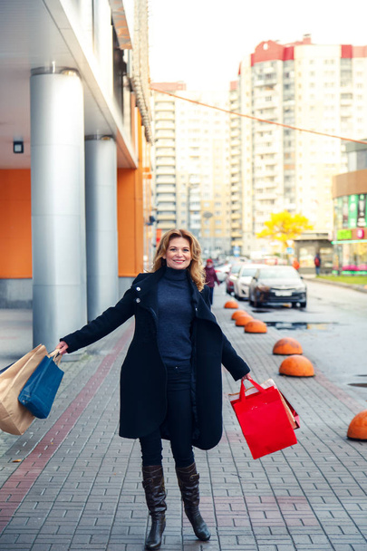 Beautiful joyful woman walks with shopping bags. Consumption, shopping, joy and sale concept.  - Photo, image