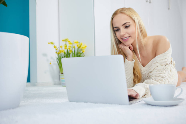 Beautiful woman working on laptop in white bedroom - Fotoğraf, Görsel