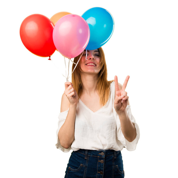 Красивая молодая девушка держит воздушный шар и делает победный жест
 - Фото, изображение