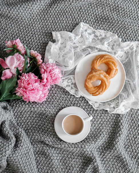 A cup of coffee with sweets and peonies on a gray background - Фото, зображення