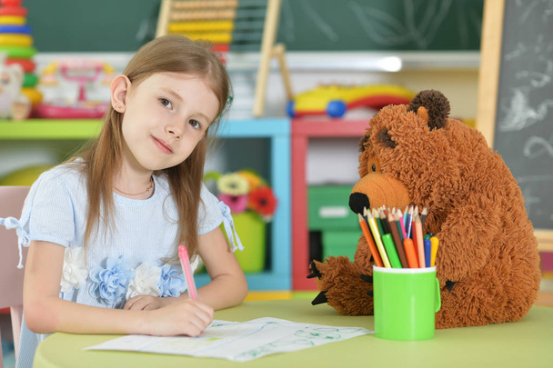 Cute schoolgirl sitting at table  and drawing - Φωτογραφία, εικόνα
