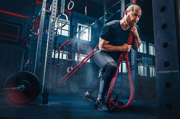 Men with battle rope battle ropes exercise in the fitness gym. - Фото, изображение