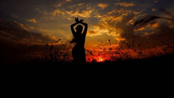 Schaduw van de vrouwelijke silhouet doet yoga op zonsondergang steppe achtergrond. - Foto, afbeelding