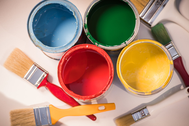 Pinceles y latas de pintura abiertas con colores
 - Foto, imagen