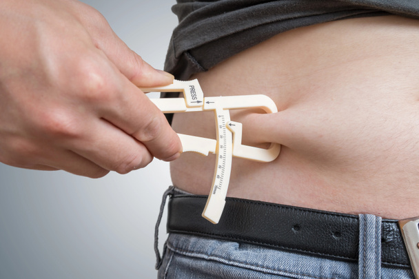 L'homme mesure la graisse corporelle sur son ventre avec étrier
. - Photo, image