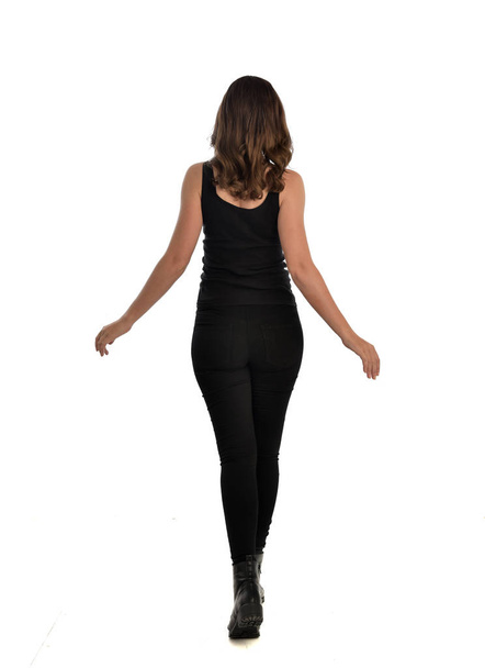 portrait complet de fille brune portant singlet noir, jeans et bottes. pose debout, face à la caméra. isolé sur fond de studio blanc
. - Photo, image