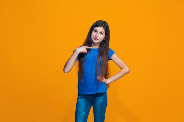 The happy teen girl standing and smiling against orange background. - Fotografie, Obrázek