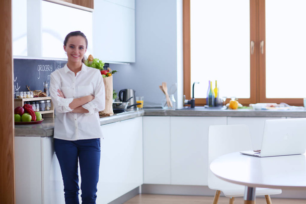 Portrait of young woman standing with arms crossed against kitchen background. Woman in the kitchen. - Foto, Imagen