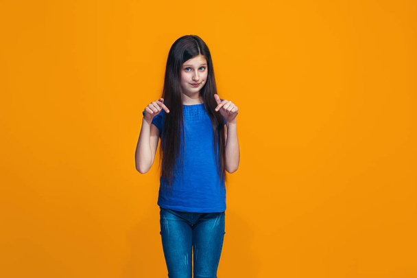 The happy teen girl standing and smiling against orange background. - Valokuva, kuva