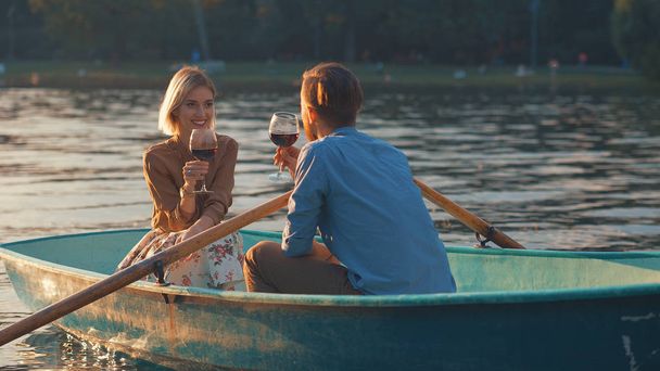Attractive couple with glasses of wine in a boat - Фото, изображение