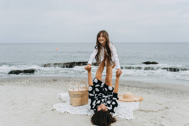 Mother and daughter holding hands and walking on beach - Foto, Imagen