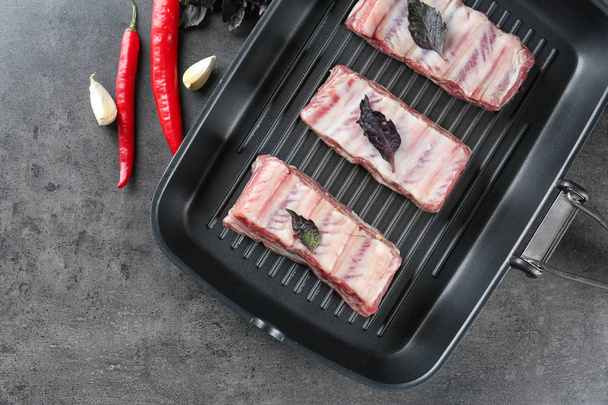 Grill pan with fresh raw pork ribs on kitchen table - Zdjęcie, obraz