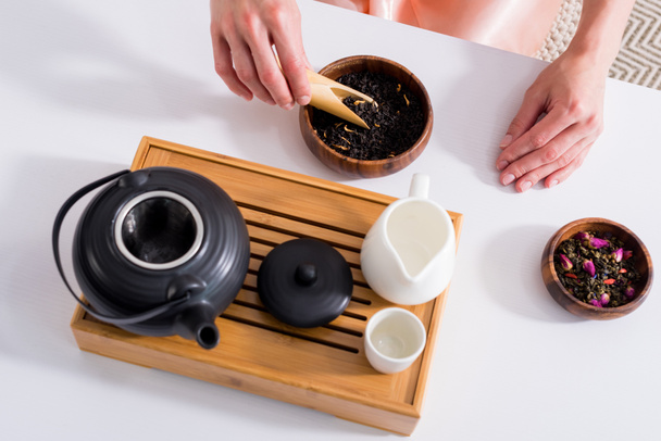 abgeschnittene Aufnahme einer Frau, die Tee kocht, während sie morgens zu Hause Teezeremonie hat - Foto, Bild