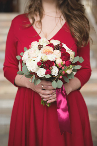 Noiva com um vestido vermelho. Dama de honra num vestido vermelho. Buquê de casamento com uma fita vermelha
 - Foto, Imagem