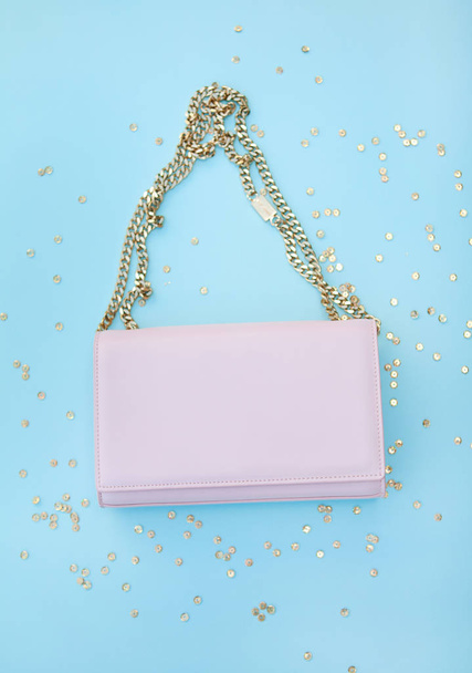Pink bag on a gold chain. Golden sequins. Blue background - Photo, Image